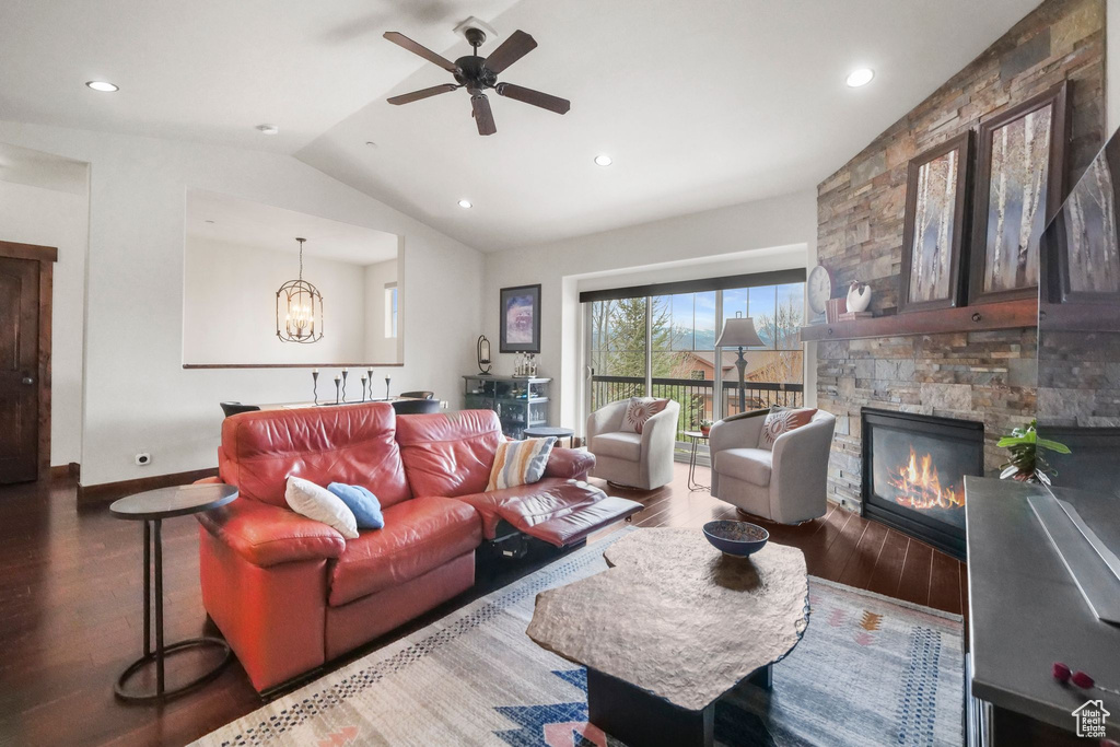 Living area with lofted ceiling, recessed lighting, ceiling fan with notable chandelier, wood finished floors, and a fireplace