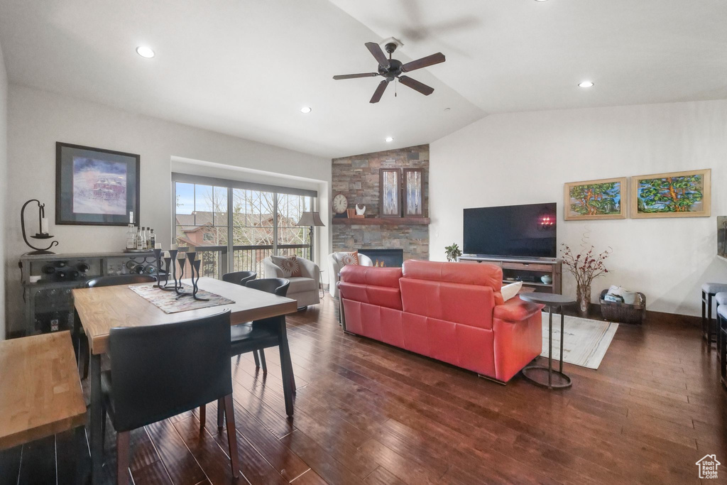 Living room featuring a ceiling fan, vaulted ceiling, recessed lighting, a stone fireplace, and wood finished floors