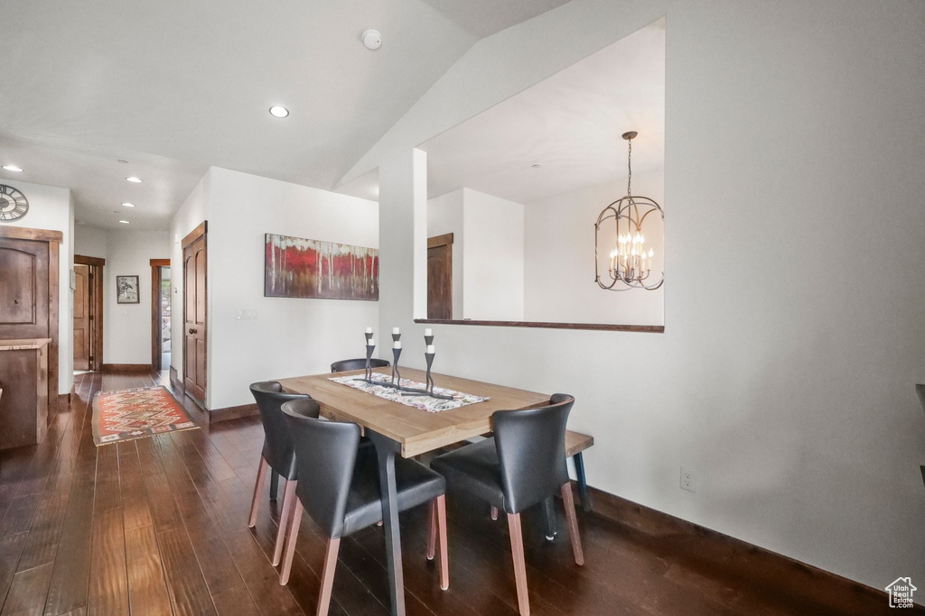 Dining space featuring a notable chandelier, dark wood-style flooring, baseboards, vaulted ceiling, and recessed lighting