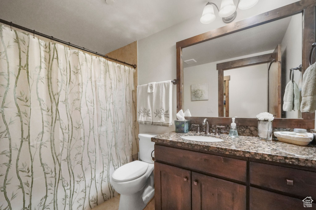 Full bath featuring toilet, vanity, and curtained shower