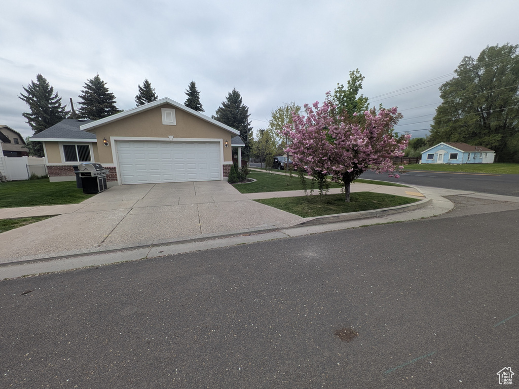 View of front of house with concrete driveway, stucco siding, an attached garage, and a front yard