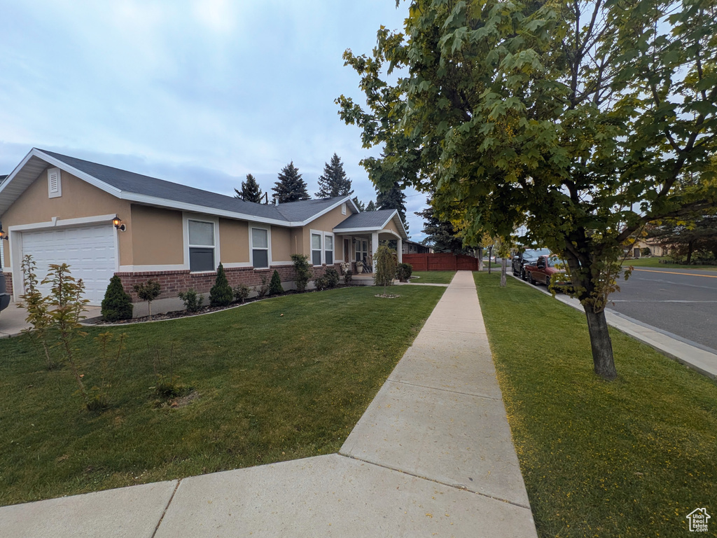 View of front facade featuring stucco siding, an attached garage, a front lawn, and brick siding