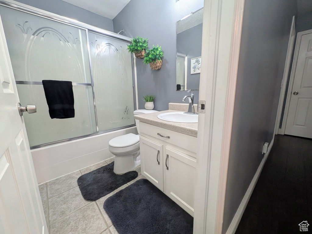 Full bath with vanity, toilet, shower / bath combination with glass door, and tile patterned floors
