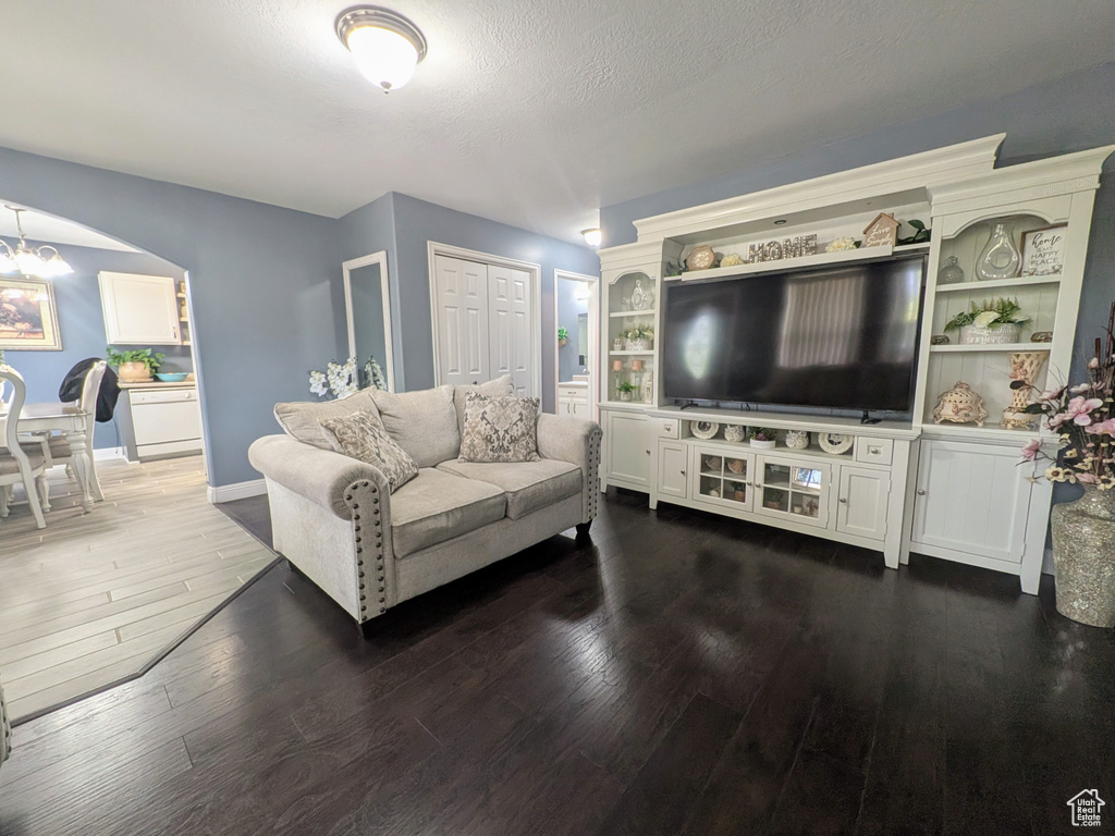 Living area featuring arched walkways, baseboards, an inviting chandelier, and wood-type flooring