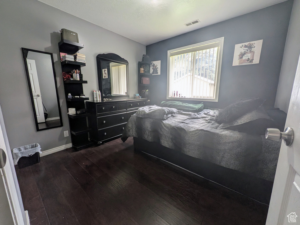 Bedroom featuring baseboards, visible vents, and dark wood finished floors