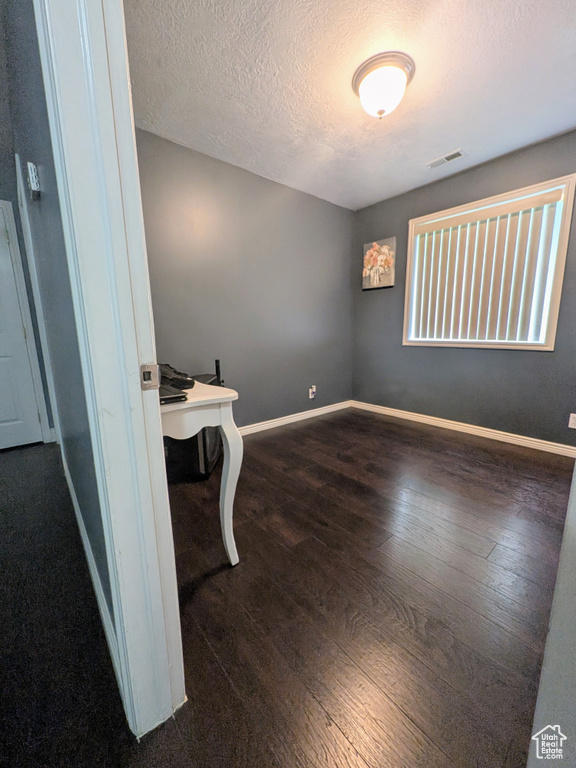 Interior space with baseboards, wood-type flooring, visible vents, and a textured ceiling