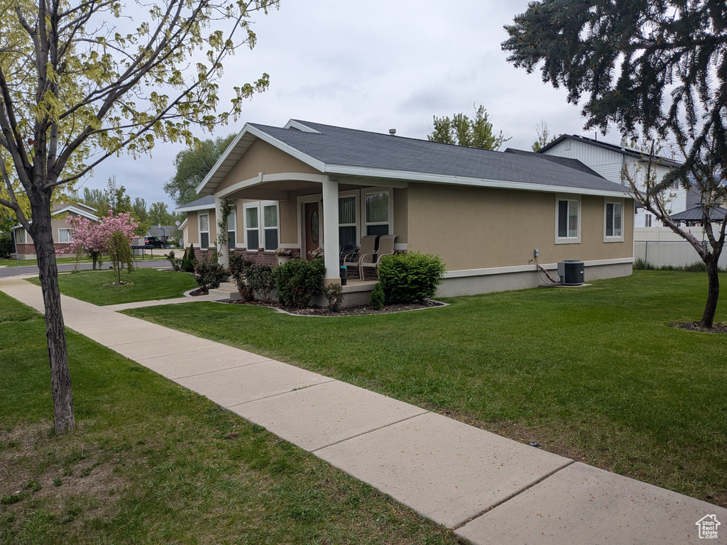 View of property exterior featuring a porch, stucco siding, a yard, and central AC unit