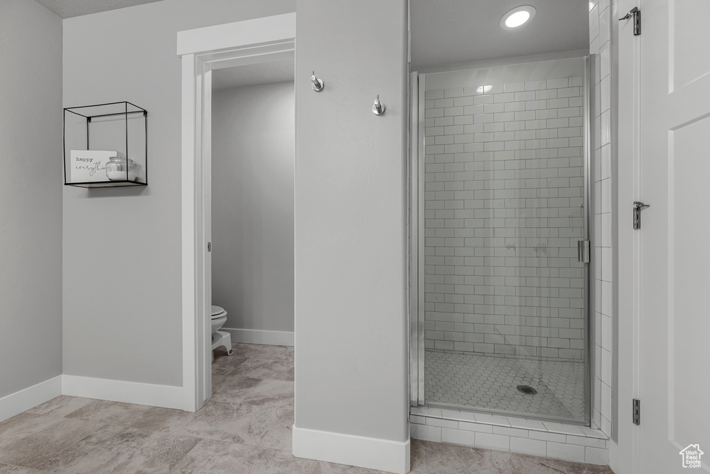 Bathroom featuring a stall shower, toilet, baseboards, and recessed lighting
