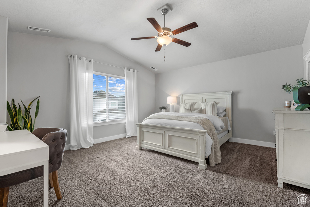 Carpeted bedroom with vaulted ceiling, ceiling fan, baseboards, and visible vents