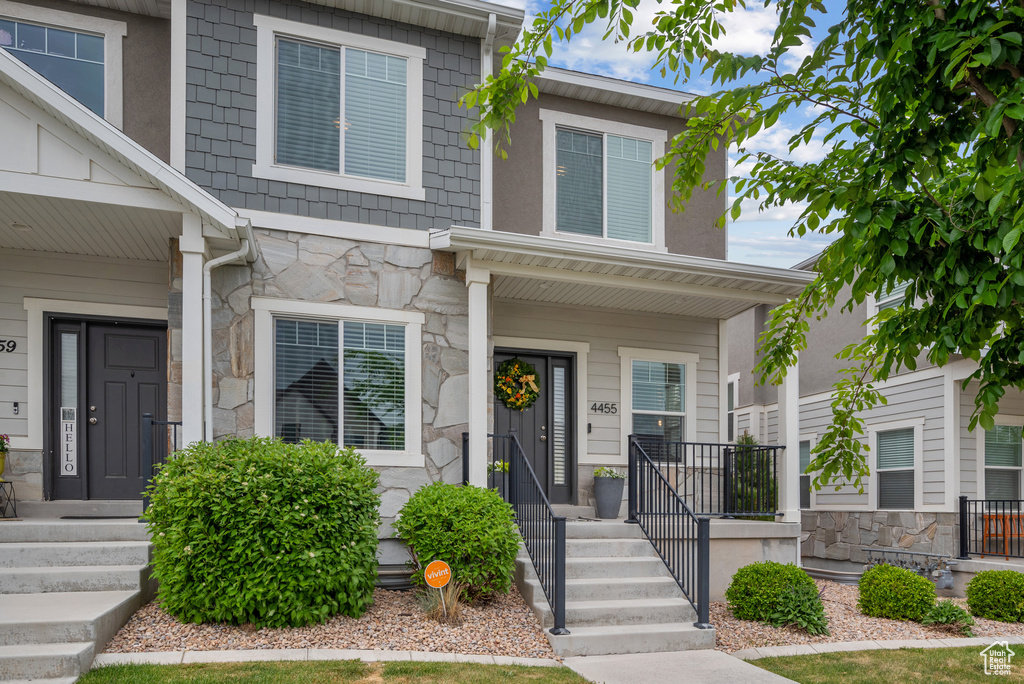 Townhome / multi-family property featuring stone siding and a porch
