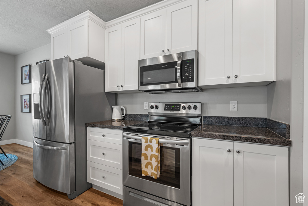 Kitchen featuring white cabinets, stainless steel appliances, and dark wood-type flooring