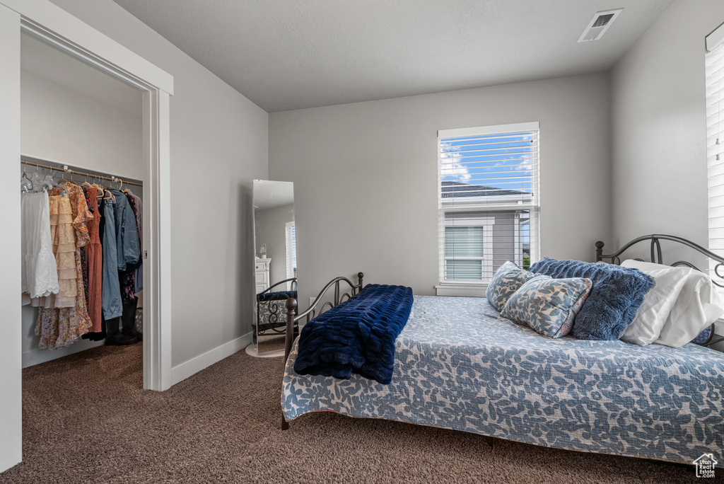 Bedroom featuring a closet, baseboards, carpet flooring, visible vents, and a walk in closet