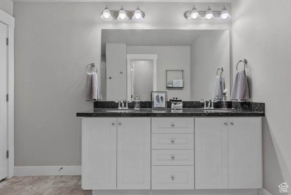 Bathroom with baseboards, double vanity, and a sink