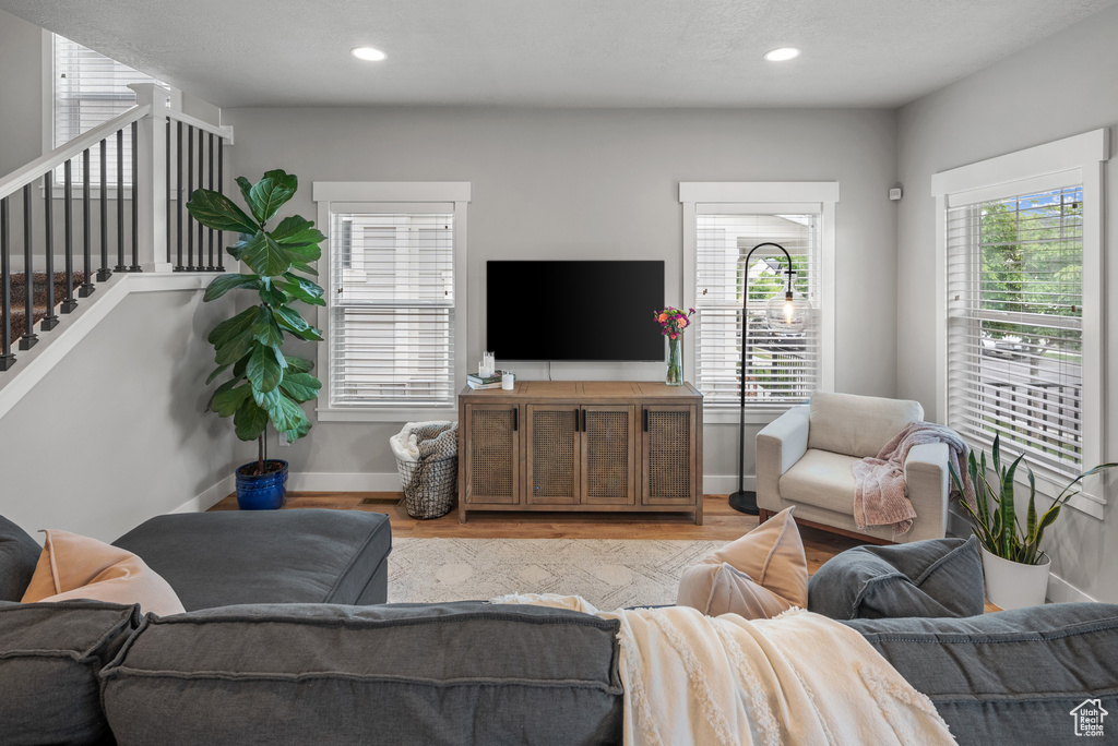 Living room featuring plenty of natural light, light wood-type flooring, stairway, and baseboards