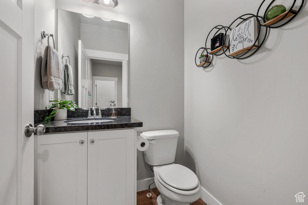 Half bath featuring toilet, baseboards, and vanity