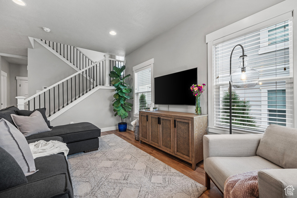 Living area featuring stairs, recessed lighting, a healthy amount of sunlight, and wood finished floors
