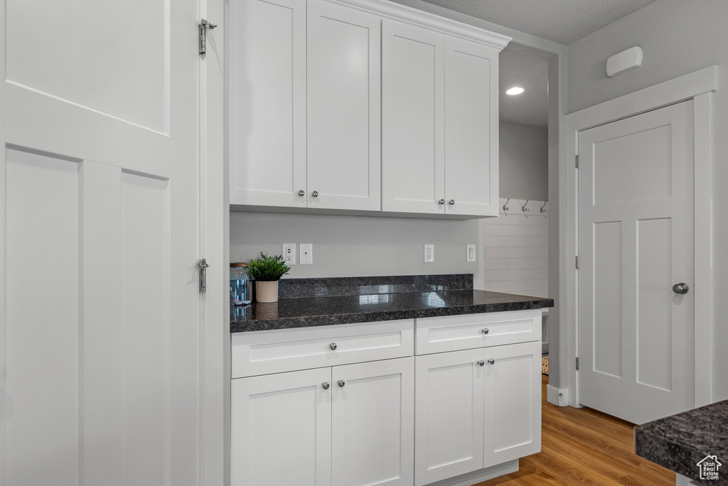 Kitchen with white cabinetry, light wood finished floors, dark stone counters, and recessed lighting