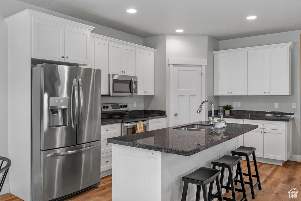 Kitchen featuring light wood finished floors, white cabinetry, appliances with stainless steel finishes, and a sink