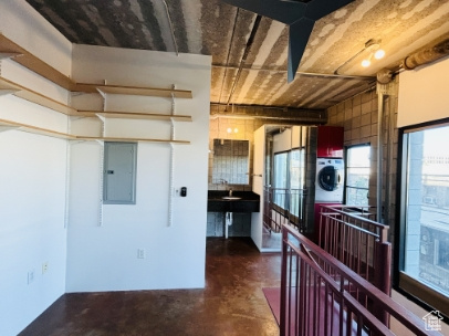 Kitchen with finished concrete flooring, stacked washer / drying machine, and electric panel