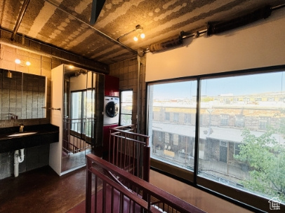 Hall with a sink, washer / clothes dryer, finished concrete flooring, and an upstairs landing