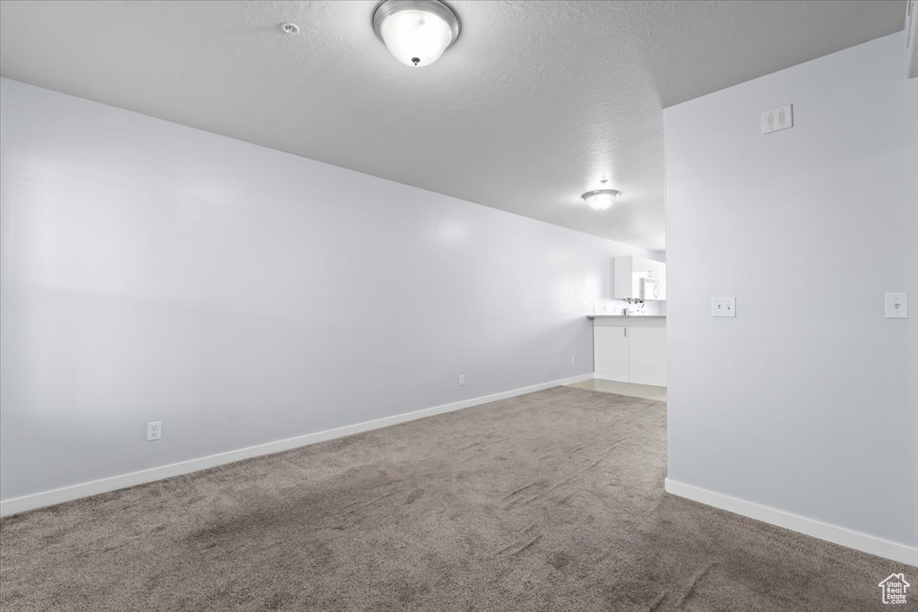 Carpeted spare room featuring baseboards and a textured ceiling
