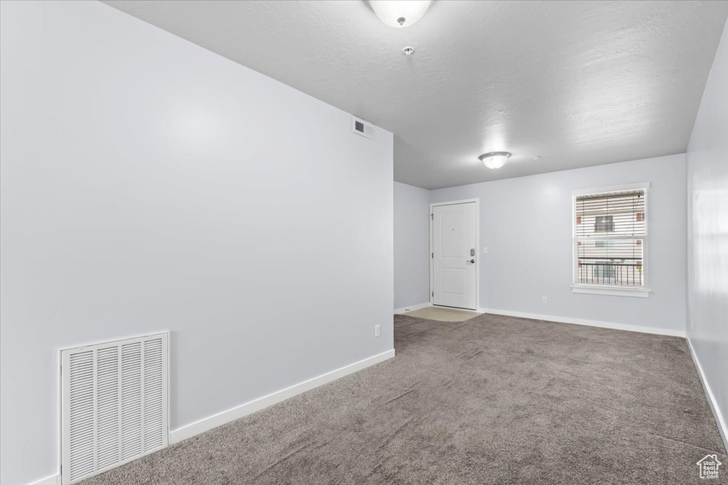 Unfurnished room with carpet, visible vents, and baseboards