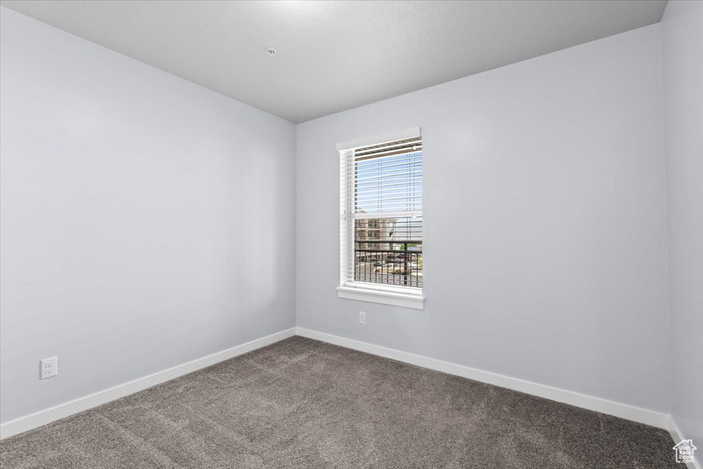 Spare room with dark colored carpet and baseboards