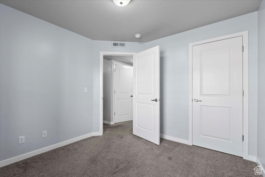 Unfurnished bedroom with carpet flooring, visible vents, and baseboards
