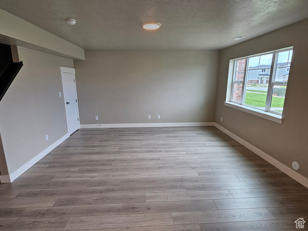 Unfurnished room featuring a textured ceiling, baseboards, visible vents, and wood finished floors
