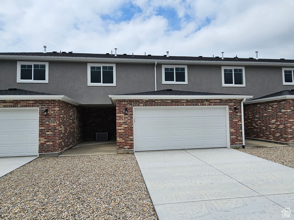 Traditional-style home featuring concrete driveway, stucco siding, a garage, and central air condition unit
