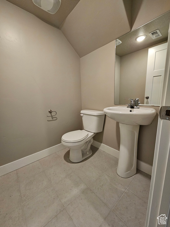 Bathroom with toilet, a sink, visible vents, baseboards, and lofted ceiling