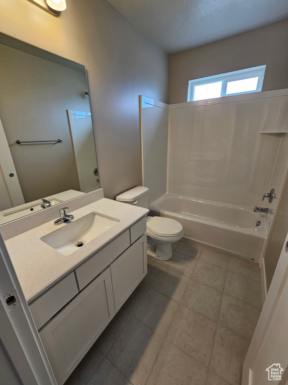 Full bathroom featuring toilet, vanity, tub / shower combination, and a textured ceiling
