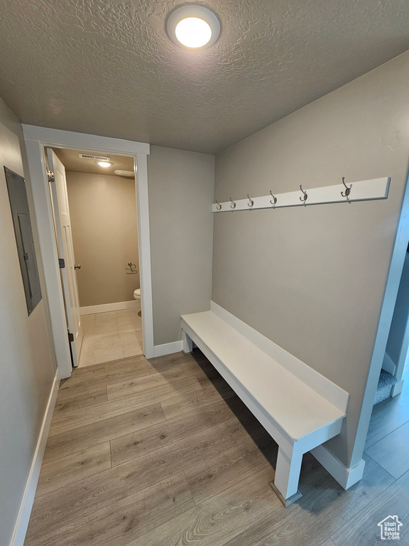 Mudroom featuring electric panel, a textured ceiling, wood finished floors, and baseboards