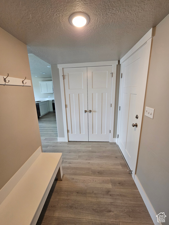 Hallway featuring a textured ceiling, baseboards, and wood finished floors