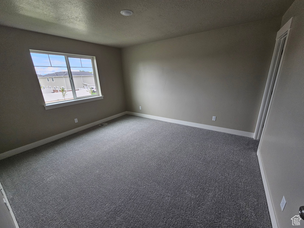 Carpeted empty room with baseboards and a textured ceiling