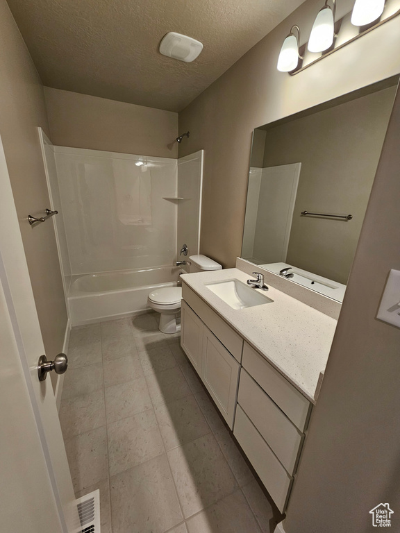 Bathroom with toilet,  shower combination, tile patterned floors, a textured ceiling, and vanity