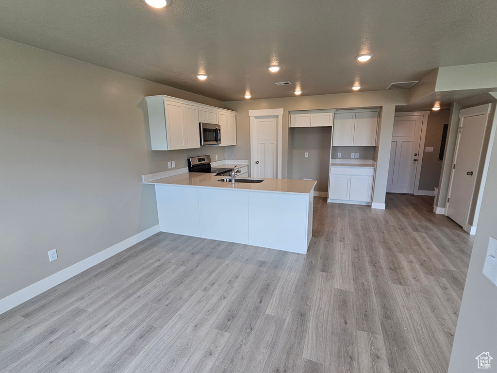 Kitchen with stainless steel appliances, baseboards, a sink, a peninsula, and light countertops