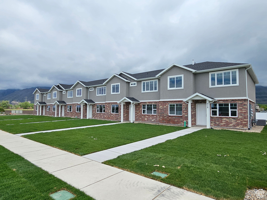 Multi unit property featuring a residential view, stucco siding, brick siding, and a front lawn