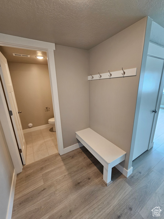 Mudroom with a textured ceiling, wood finished floors, and baseboards