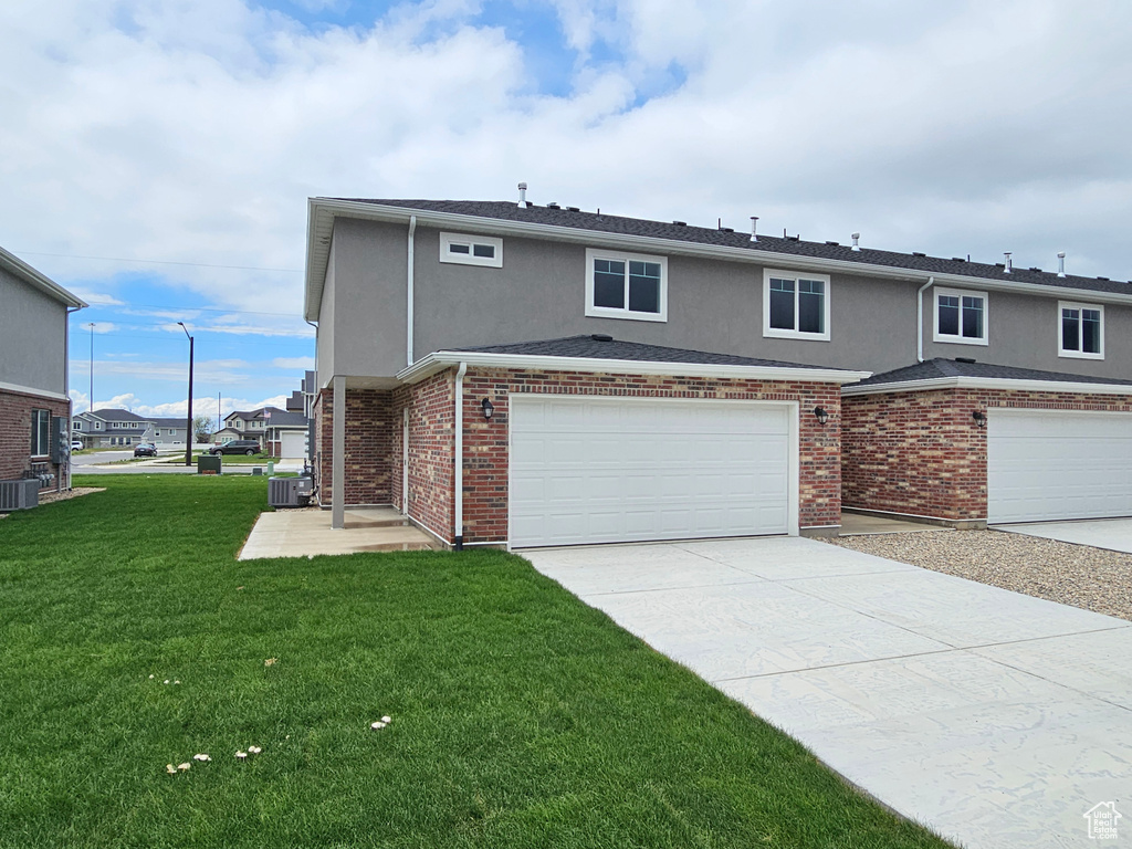 View of front of home featuring driveway, a garage, stucco siding, a front lawn, and cooling unit