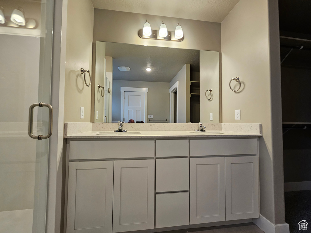 Bathroom featuring a sink, double vanity, and a shower stall