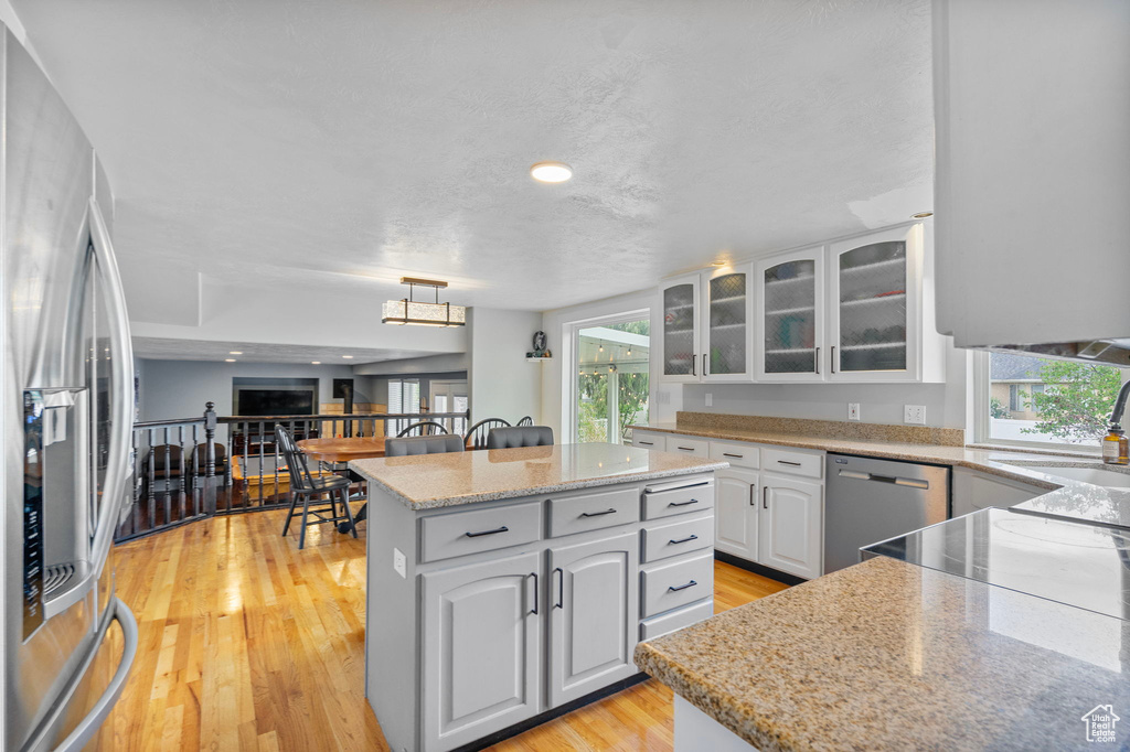 Kitchen featuring light wood-style floors, a healthy amount of sunlight, appliances with stainless steel finishes, and a center island