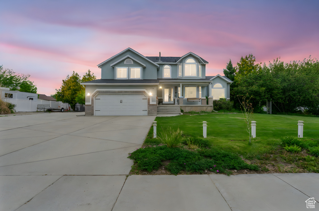 Traditional home featuring a lawn, driveway, a garage, stucco siding, and a porch