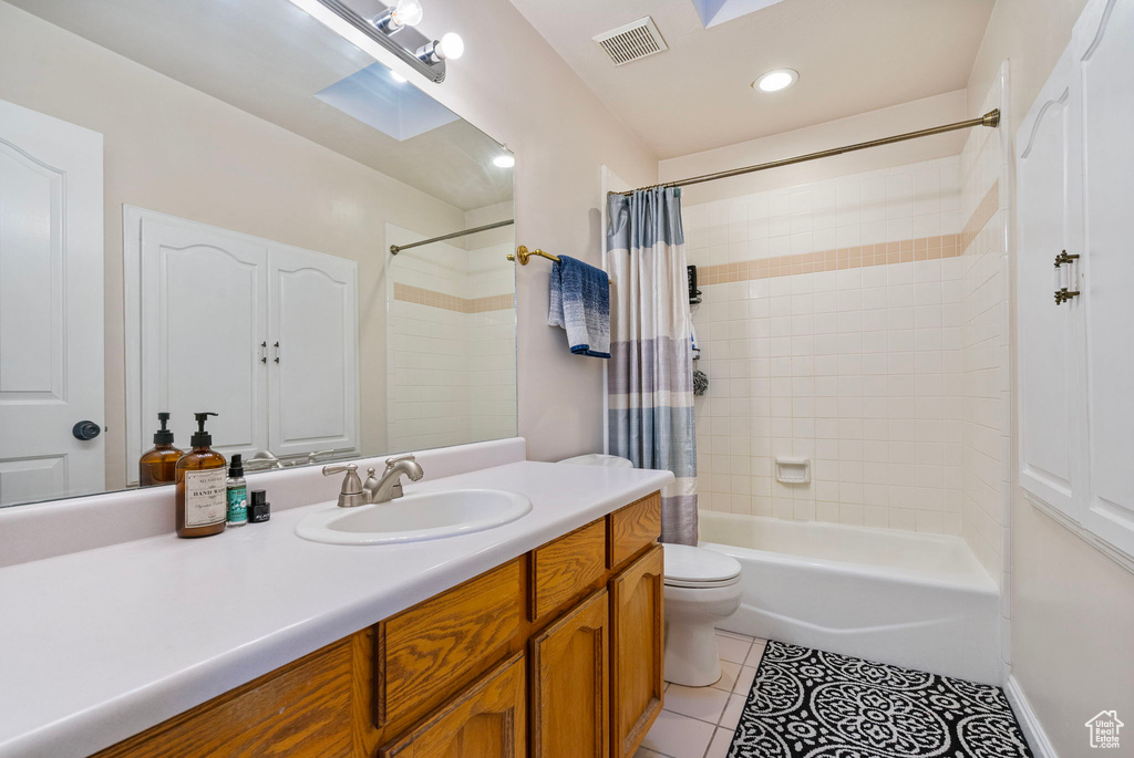 Full bath featuring toilet, visible vents, tile patterned floors, vanity, and shower / bath combo