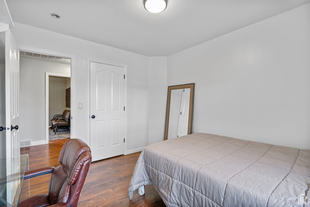 Bedroom with baseboards, visible vents, and wood finished floors