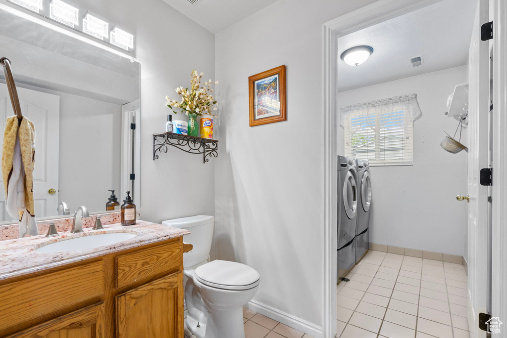 Bathroom featuring toilet, washing machine and clothes dryer, tile patterned floors, visible vents, and vanity