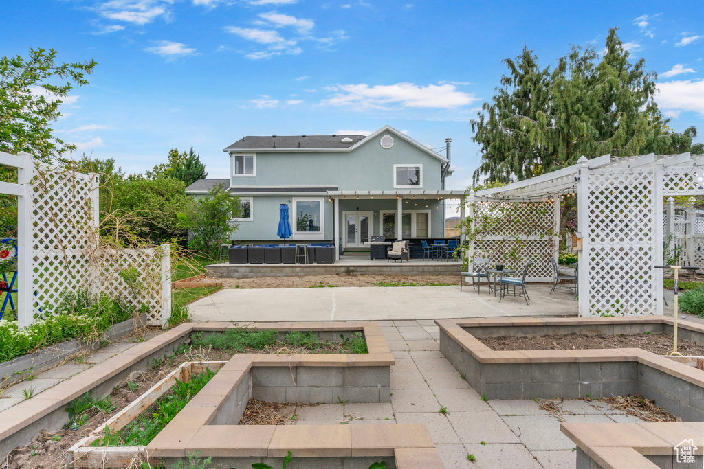 Rear view of house featuring a patio, stucco siding, a garden, and fence