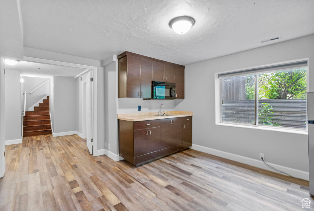 Kitchen featuring a sink, light wood-type flooring, visible vents, light countertops, and black microwave
