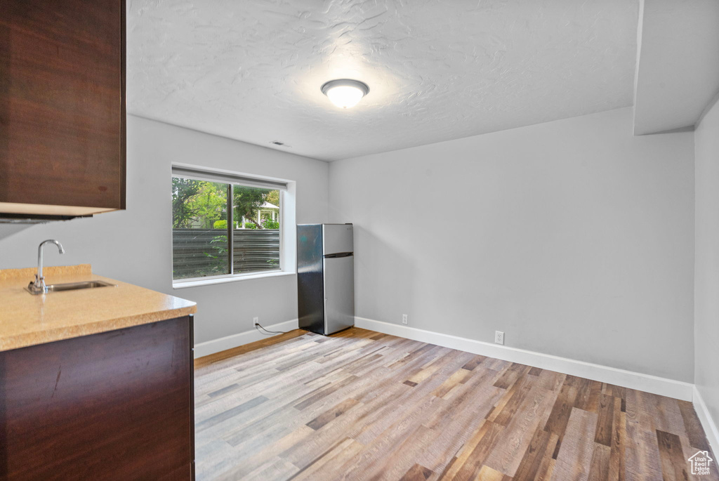 Interior space with baseboards, a textured ceiling, light wood finished floors, and a sink
