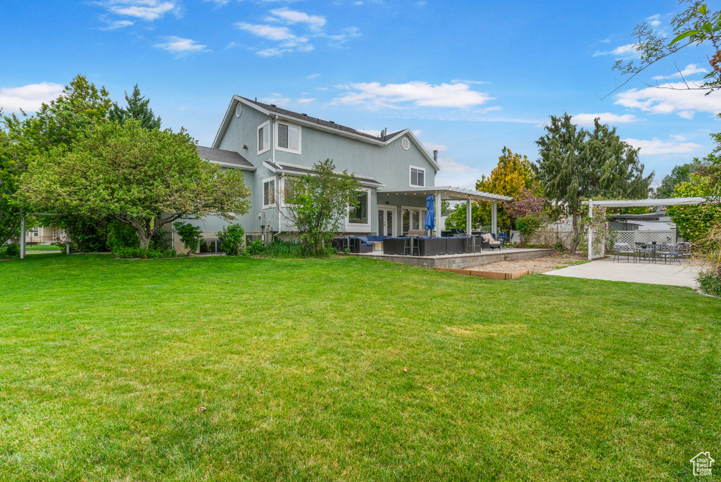 Back of house featuring a yard, a patio area, stucco siding, and fence